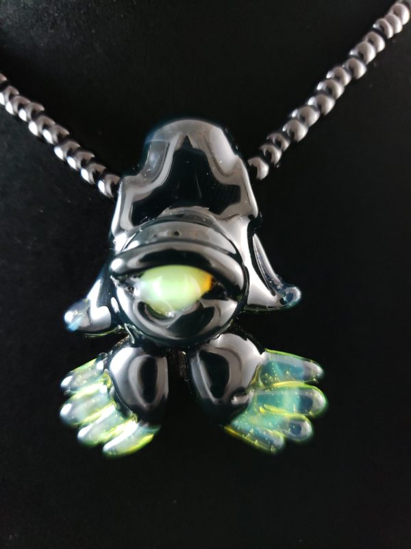 black glass alien creature pendant with green eye and feet