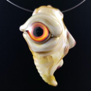 glass creature face pendant with orange and yellow eye