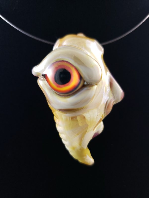 glass creature face pendant with orange and yellow eye